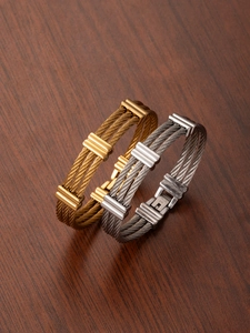 Close-up of gold and silver stainless steel cable bracelets with textured metal clasps