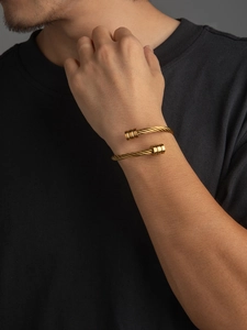 Detail of 18k gold plated stainless steel cable twist cuff bracelet on male wrist