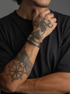 Detailed view of gold and silver stainless steel cable wire bracelets on tattooed arm