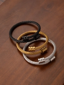 Detailed close-up of twisted cable titanium steel bangles in black, gold, and silver finishes