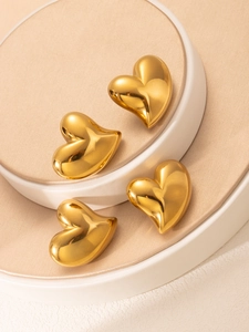 Détail macro de boucles d'oreilles cœur plaquées or 18 carats sur socles de présentation