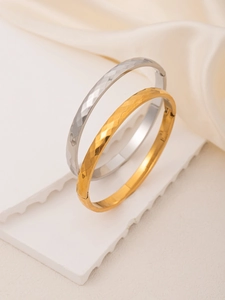 Detail of hammered 18K gold and silver plated titanium steel bangles on display