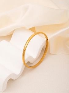 Detail of 18K gold plated bangle featuring a delicate hammered texture and shiny finish