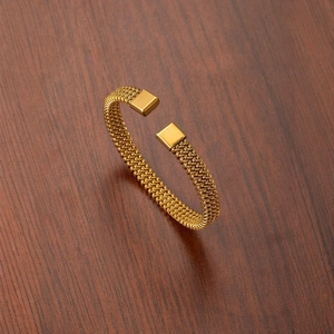 Gold woven mesh open ring with honeycomb texture on a dark wood background
