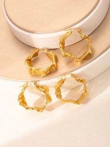 Gros plan sur des boucles d'oreilles C en plaqué or 18k avec texture de lave ondulée