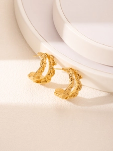 Détail de créoles en forme de C plaquées or 18 carats avec texture de lave sur podium