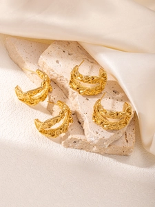 Détail des boucles d'oreilles C plaquées or 18 carats avec texture lave sur fond satiné
