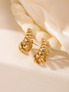 Détail de boucles d'oreilles spirales plaquées or 18 carats sur plateau soie