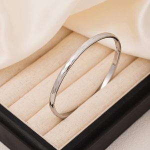 Polished titanium steel rhombic bangle with hammered texture in an elegant jewelry box