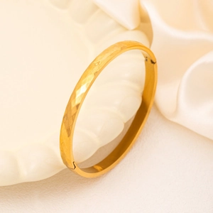 Polished 18K gold plated titanium bangle with a unique geometric hammered texture design