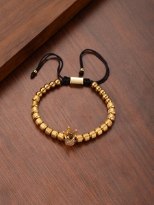 Detailed macro view of gold crown charm and woven beads on a stylish wristband
