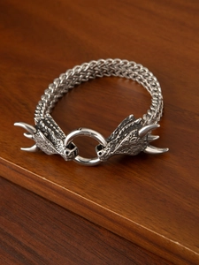 Macro detail of men's vintage dragon head woven chain bracelet in antique silver steel