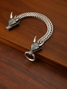Macro shot of Viking wolf head bracelet with intricate silver engraving and scale chain