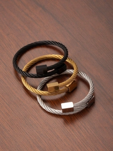 Detailed view of three-color stainless steel wire cable bracelets on a wooden surface