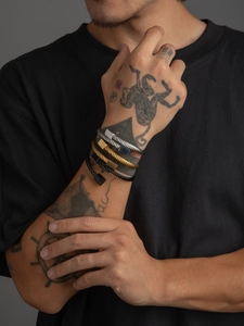 Detail showing various wire rope bracelets with metallic square clasps on a model