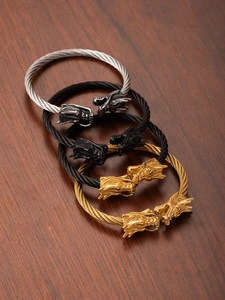 Close-up of triple-tone steel cable bracelets with intricately carved dragon heads