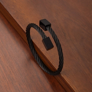 Black twisted cable stainless steel open cuff bracelet with square ends on wood background