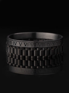 Macro detail of black stainless steel ring featuring Roman numerals and watchband texture