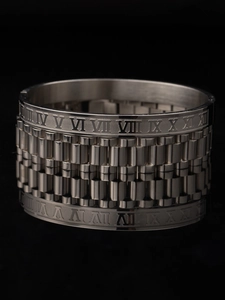 Detail of silver stainless steel cuff featuring Roman numerals and watch band texture