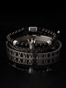 Dettaglio del bracciale con perline a corona e polsino con numeri romani su specchio nero