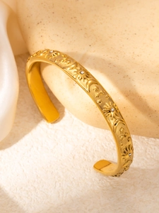 Detalle de los relieves de sol y luna en brazalete de acero inoxidable bañado en oro 18k