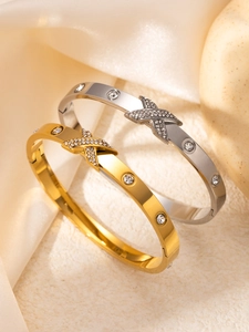 Détail de bracelets en acier inoxydable doré et argenté avec motif X et cristaux scintillants