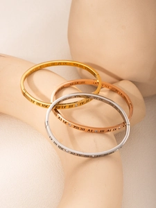 Close-up of titanium bangles with Roman numerals and crystals in gold, rose gold and silver