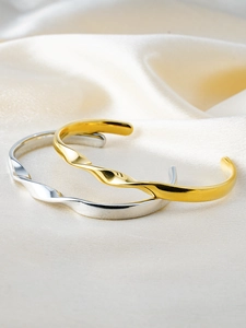 Detailed close-up of polished gold and silver Mobius rings on elegant silk fabric