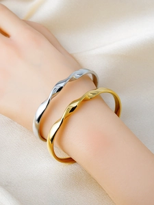 Detailed view of polished Mobius gold and silver bangles with elegant wavy texture