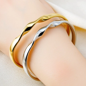 Minimalist Möbius twisted gold and silver bangles worn on wrist in a high-polish finish
