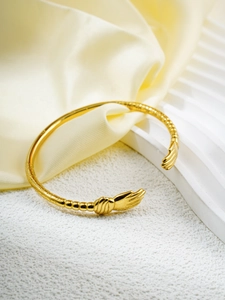 Detailed macro view of 18k gold plated C-shaped bangle featuring intricate hand-shaped ends