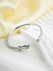 Detailed view of silver hugging hands open cuff bracelet with intricate engraved textures