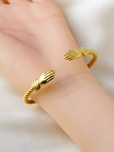 Close-up of 18k gold plated C-shaped hug bracelet with detailed hand design on a model