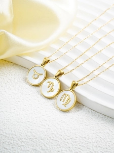 Detail of 18k gold plated zodiac necklaces with mother of pearl pendants on white texture