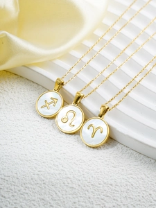 Detail of 18k gold zodiac pendants with white shell inlay on elegant display pedestals