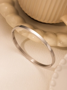 Macro view of minimalist silver bangle showing smooth surface and invisible hinge closure