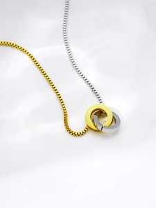 Macro detail of interlocking gold and silver rings on a two-tone box chain necklace