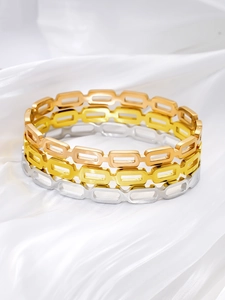 Detailed shot of three stainless steel hollow bangle bracelets in gold rose gold and silver