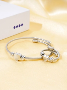 Close-up of cable wire heart bracelet and ring set on elegant yellow silk background