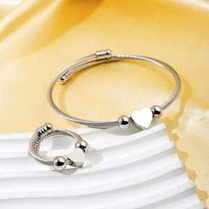 Silver stainless steel heart bracelet and ring set on golden silk backdrop
