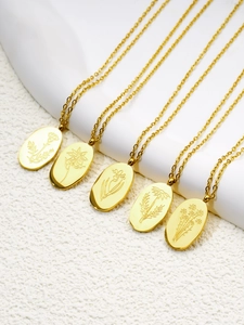 Détail de cinq colliers en acier doré avec pendentifs ovales aux gravures florales