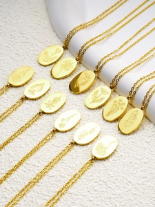 Détail de pendentifs floraux ovales plaqués or 18 carats avec gravures sur support blanc