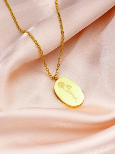Gros plan du collier pendentif marguerite dorée sur un tissu en satin rose doux