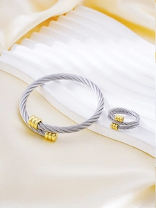 Detail of twisted cable steel wire bracelet and ring with gold ends on silk background
