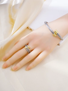Detail of twisted steel cable jewelry set featuring a gold-toned bangle and adjustable ring