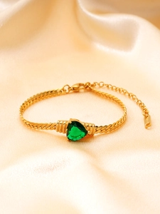Détail d'un bracelet doré à maillons plats avec pierre verte en cœur et fermoir mousqueton