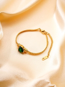Détail du bracelet en acier inoxydable doré avec pierre précieuse cœur vert sur soie