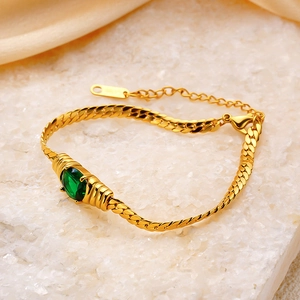 Détail d'un bracelet chaîne serpent dorée avec pierre verte et fermoir mousqueton