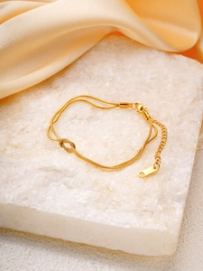 Détail d'un bracelet double chaîne serpent plaqué or avec nœud central et fermoir homard