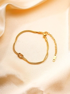 Détail du bracelet double maille serpent dorée avec noeud sur tissu de soie champagne